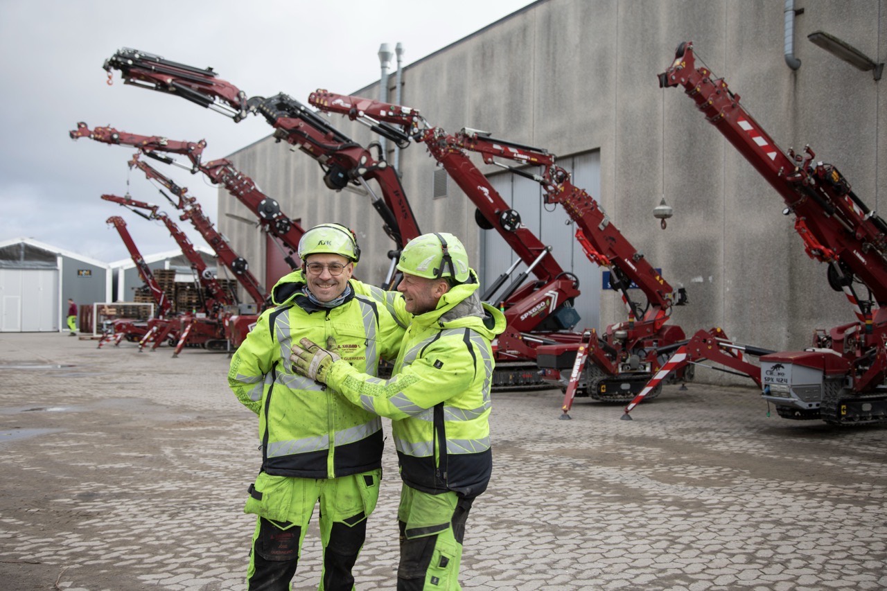 To medarbejdere fra A. Sømod foran rækken af minikraner